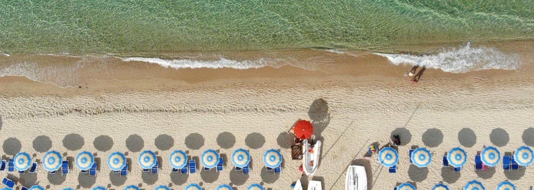 Stunning aerial view of Geremeas Beach in Sardinia, showcasing vibrant umbrellas and crystal-clear waters.